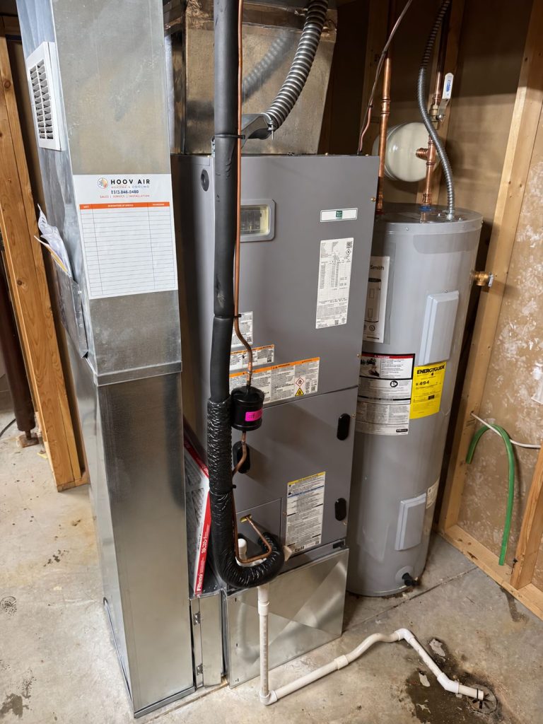 Air handler and electric water heater installed side by side with a Hoov Air service record card