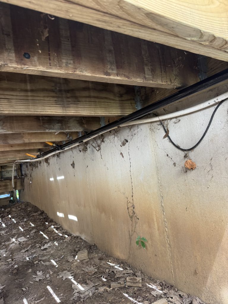 Black iron gas line run along the floor joists in a crawl space by Hoov Air